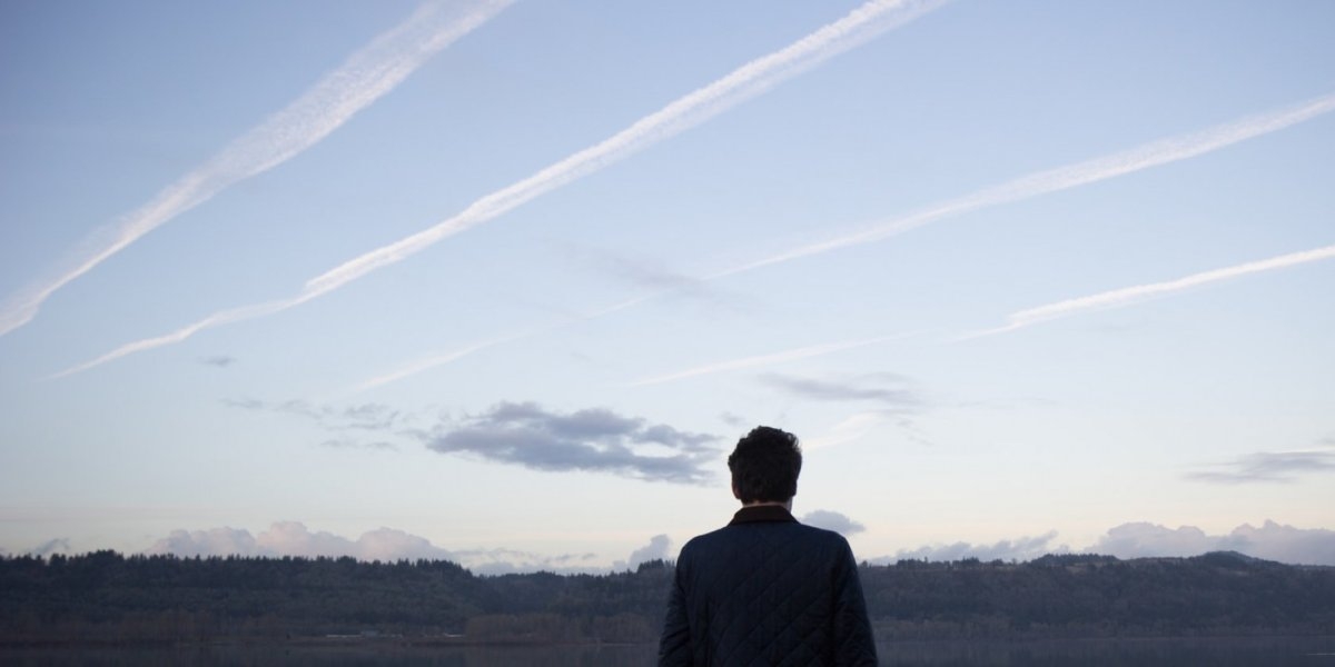 En mann ser på flystriper på himmelen