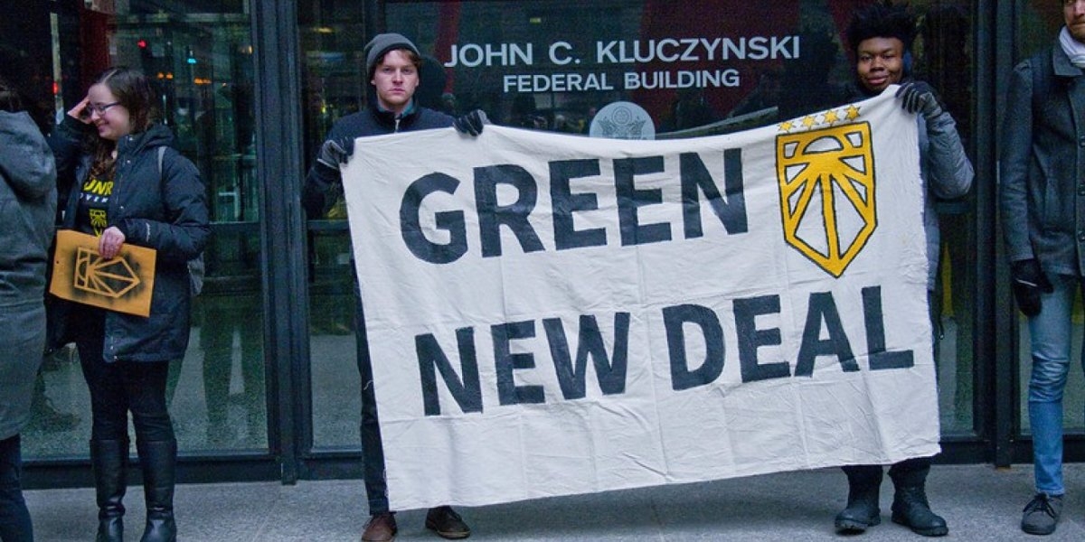 Foto av to unge menn som holder opp en plakat der det står "Green new deal".